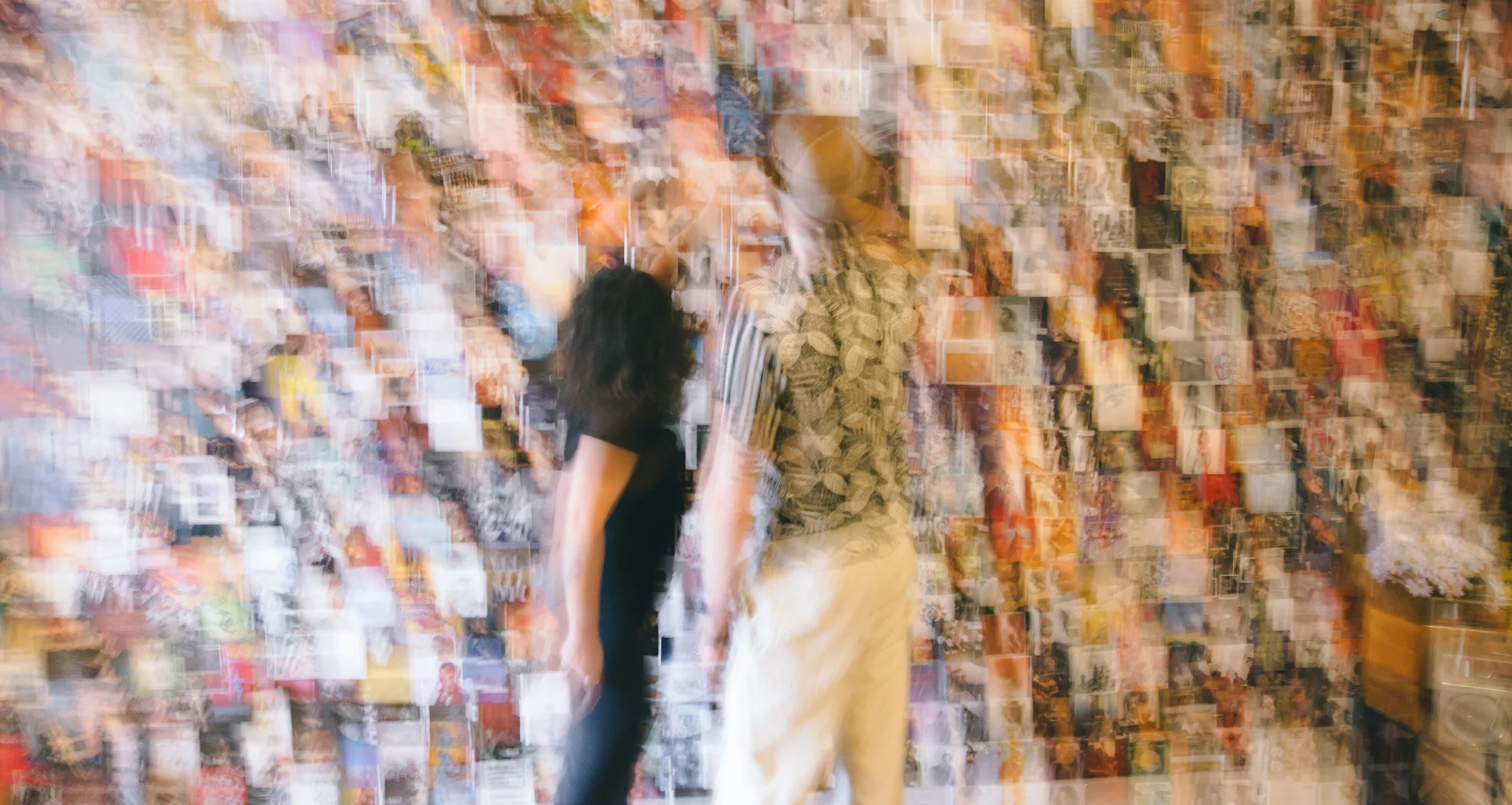 A blurred photo of Claudia and Reid reviewing clippings on a wall